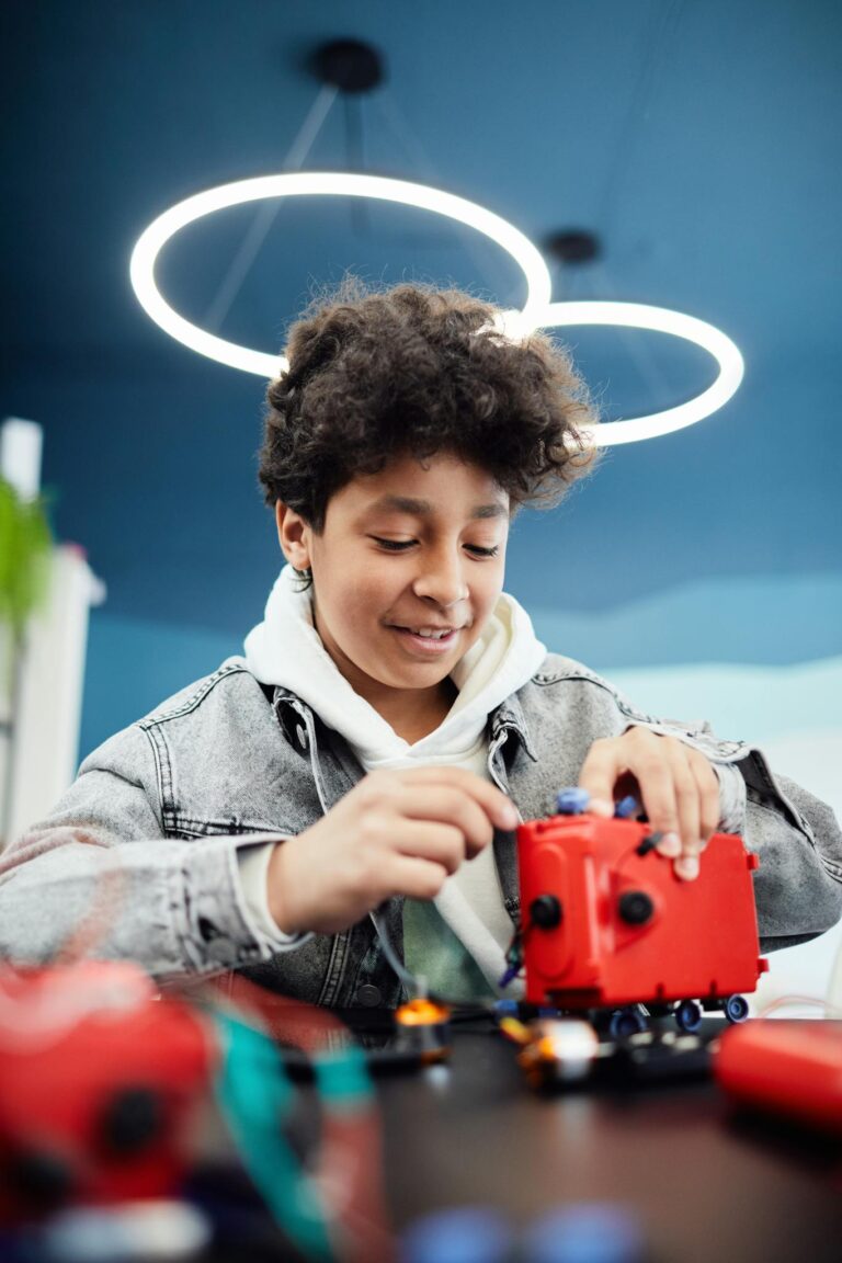 A teenage boy focusing on assembling a robotic project indoors at school.